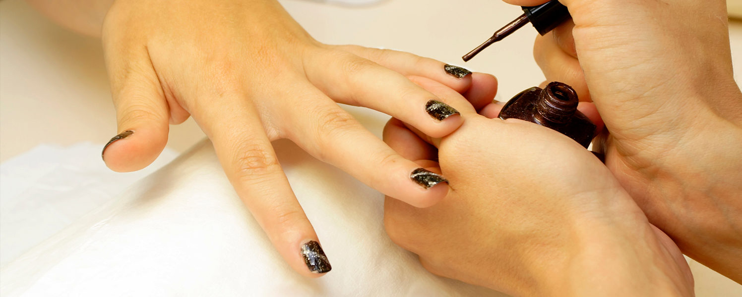 woman getting her nails painted dark